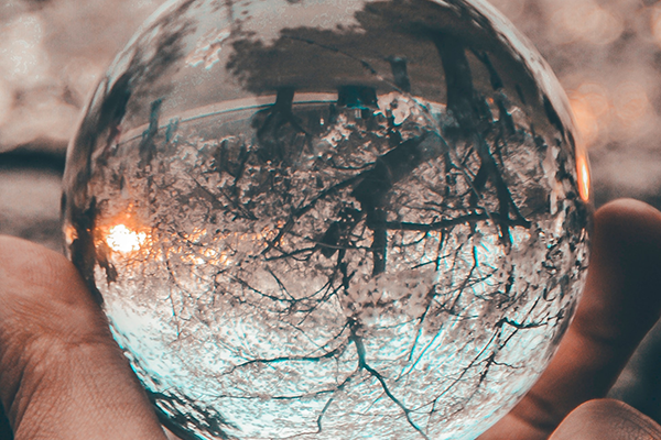 hand holding glass orb reflecting the world upside down