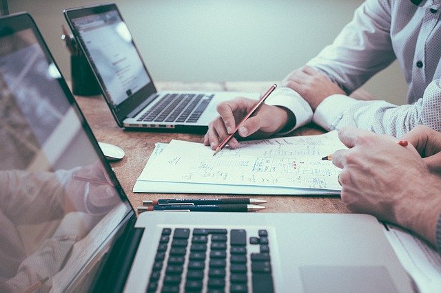 In an office at a desk a business man in a shirt writes with a pencil.